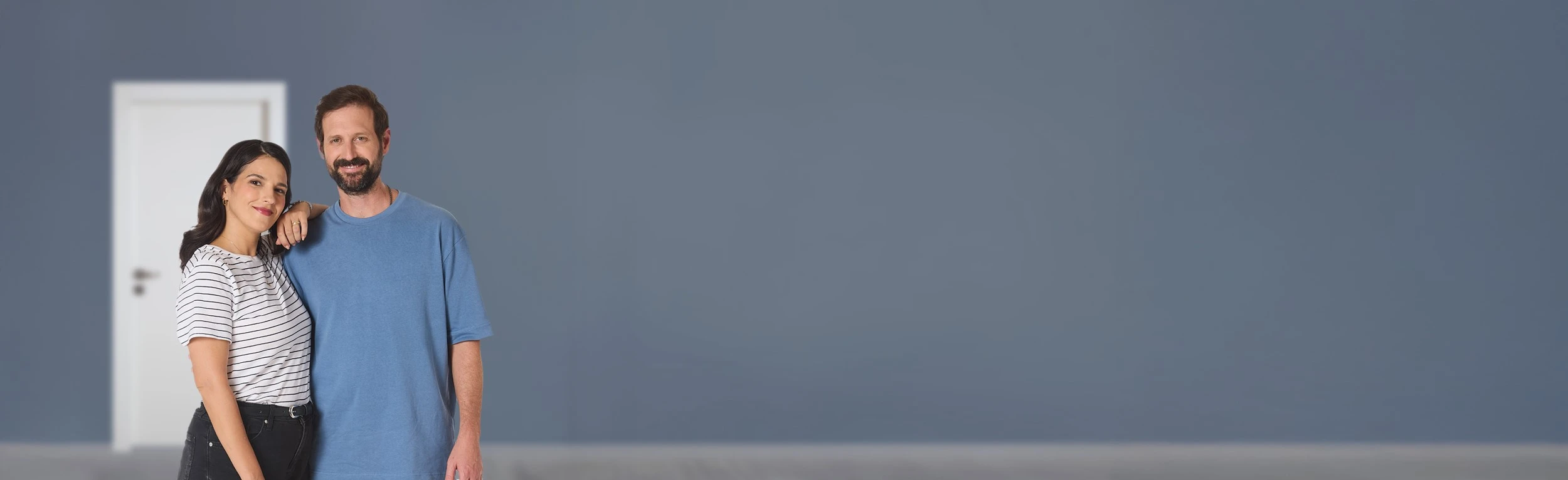 זוג מחובק על רקע קיר אפור ודלת פנדור לבנה